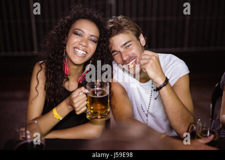 Porträt von lächelnden Freunde mit Bierkrügen sitzt am Tisch im Nachtclub Stockfoto