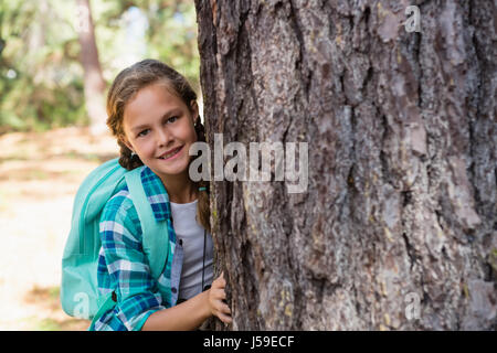 Porträt von lächelndes Mädchen versteckt sich hinter dem Baum Stockfoto