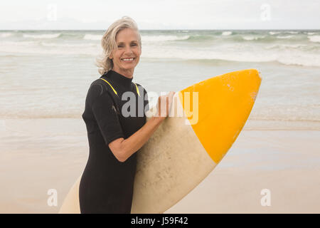 Porträt der lächelnde Frau, die Surboard stehen am Ufer am Strand Stockfoto