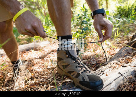 Mann binden Bootlaces im Wald an einem sonnigen Tag Stockfoto