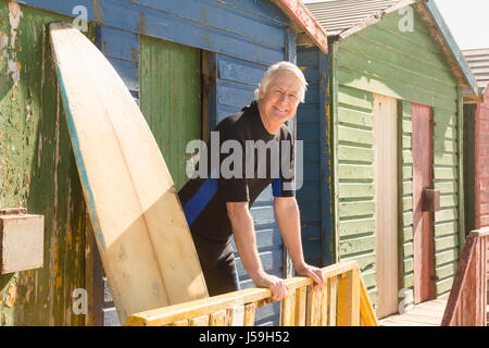 Portrait von lächelnden senior Mann stützte sich auf Geländer gegen Strandhütte Stockfoto