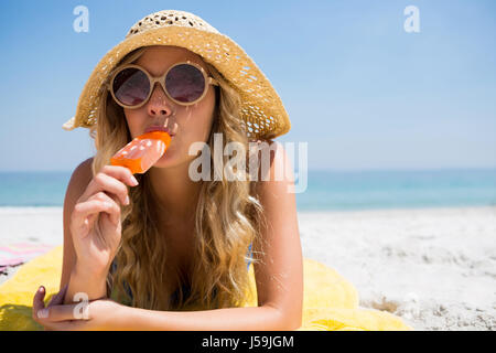 Portrait der schönen Frau essen Eis am Stiel auf sonnigen Tag am Strand entspannen Stockfoto