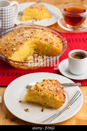 Shamali (Grieß Kuchen, Basbousa) auf weißen Tellern serviert, mit Kaffee und Tee Stockfoto