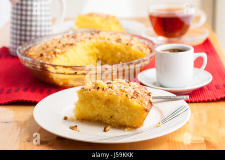 Shamali (Grieß Kuchen, Basbousa) auf weißen Tellern serviert, mit Kaffee und Tee Stockfoto