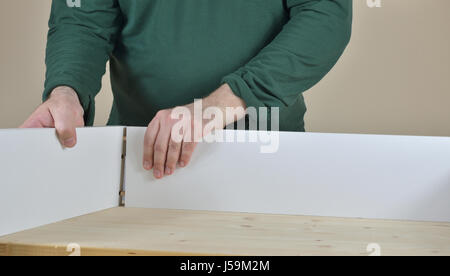 Mann, die zwei Seiten einer Schublade am Arbeitstisch anbringen Stockfoto