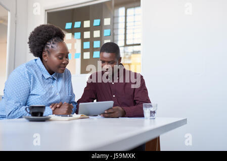 Konzentrierte sich jungen afrikanische Kollegen mit einem Tablet in einem modernen Büro Stockfoto