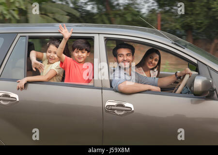 Kinder, deren Eltern aus Autofenster winken Stockfoto