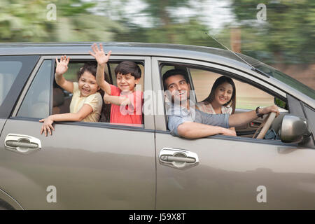 Kinder, deren Eltern aus Autofenster winken Stockfoto