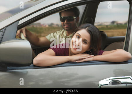 Entspannen Sie sich auf Autotür während Autofahrt junge Frau Stockfoto