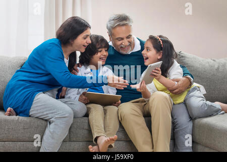 Glücklich Enkel mit digital-Tablette mit Großeltern auf sofa Stockfoto