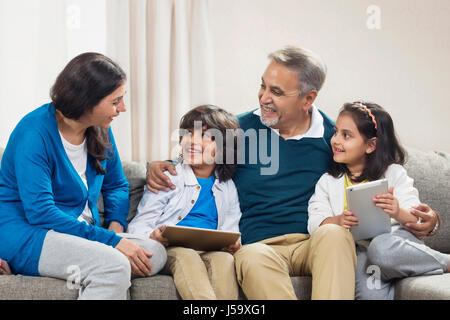 Lächelnde Enkel mit digital-Tablette mit Großeltern auf sofa Stockfoto