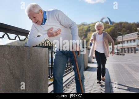 Im Alter von Rentner mit Schmerzen in der Brust auf der promenade Stockfoto