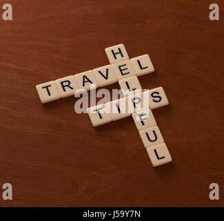 Kreuzworträtsel mit Worten hilfreiche Reisetipps. Welt-Reise-Konzept. Elfenbein Fliesen mit Großbuchstaben auf Mahagoni Brett. Stockfoto