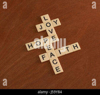 Kreuzworträtsel mit Worten glaube, Hoffnung, Liebe. Glaubens-Konzept. Elfenbein Fliesen mit Großbuchstaben auf Mahagoni Brett. Stockfoto