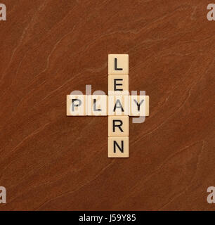Kreuzworträtsel mit Worten lernen und spielen. Bildungskonzept. Elfenbein Fliesen mit Großbuchstaben auf Mahagoni Brett. Stockfoto
