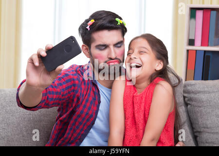 Vater tragen Make-up funny Face-sitting mit Tochter nehmen Selfie ziehen Stockfoto