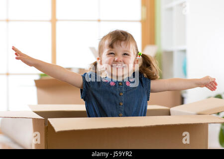 Lachendes Kind Mädchen sitzen im inneren Karton Boxe in ihrem neuen Zuhause Stockfoto