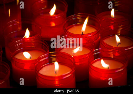 Große Gruppe von roten Kerzen leuchten im Dunkeln Stockfoto