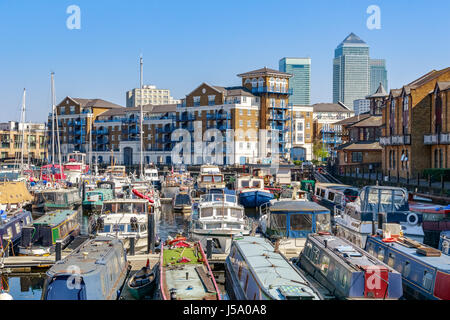 Boote und Yachten vor Anker in Limehouse Basin Marina in London mit Canary Wharf im Hintergrund Stockfoto