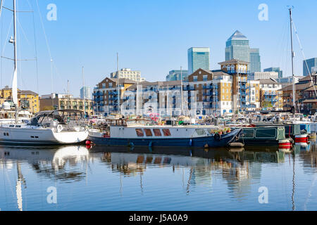 Boote und Yachten vor Anker in Limehouse Basin Marina in London mit Canary Wharf im Hintergrund Stockfoto