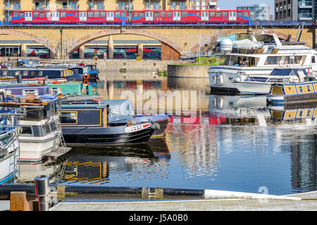 Boote und Yachten vor Anker in Limehouse Basin Marina in London mit dem Zug vorbei in den Hintergrund Stockfoto