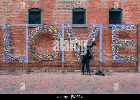 Tourist vor dem Mathew Rosenblatt Wort Liebe geschrieben mit Schlössern, Vorhängeschlösser, Liebe Symbol, Liebeskonzept, valentine, The Distillery District, Toronto. Stockfoto