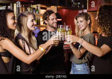 Glückliche Freunde Toasten Biergläser stehend durch Zähler in Nachtclub Stockfoto