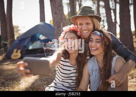 Glückliche Freunde klicken Selfie beim Zelten im Wald auf sonnigen Tag Stockfoto