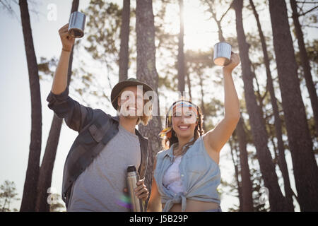 Glückliches Paar halten Kaffeetassen beim camping im Wald Stockfoto