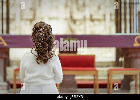 Mädchen mit weißen Kleid in der Kirche am Tag ihrer Erstkommunion Stockfoto