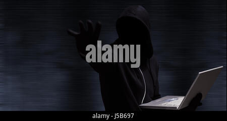 Hacker halten Laptop beim gestikulieren auf schwarzem Hintergrund Stockfoto
