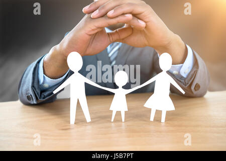 Hand zum Schutz einer Familie in Papier gegen Holztisch Stockfoto