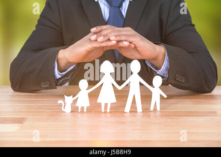 Schutz der Familie in Papier mit seinen Händen gegen Bäume in Graslandschaft Underwriter Stockfoto