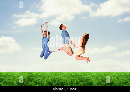 Glückliche Freunde gegen bewölktem Himmel springen Stockfoto