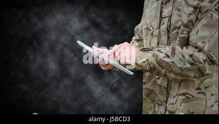 Digital Composite Soldaten Mittelteil mit Tablet schwarz Grunge Hintergrund Stockfoto