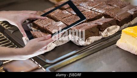 Digital Composite Hände fotografieren Brownie durch Tablet-PC Stockfoto