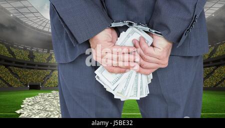 Digital Composite Mittelteil der Geschäftsmann mit Handschellen und Geld im Fußballstadion, Korruption darstellt Stockfoto