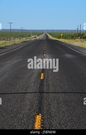 U.S. Highway 385 auf dem Weg zum Big Bend National Park erstreckt sich lang und Meerenge in die Ferne von Fort Stockton, Texas Stockfoto