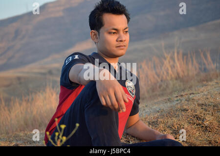 Junger Mann sitzt in der Nähe von Berg, Pune, Maharashtra Stockfoto