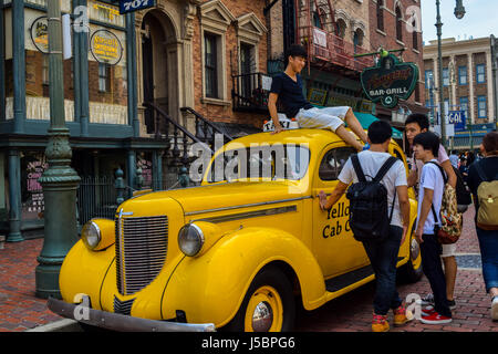 Jungen genießen eine lustige Samstag, goofing und spielt herum ein yellow Cab mit Freunden in Universal Studios Japan (USJ), Osaka, Japan. Stockfoto