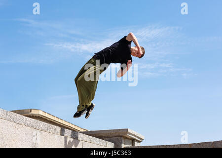 Junge Mann tut ein Back flip mit einer Umdrehung. Parkour im urbanen Raum. Sport in der Stadt. Sportliche Aktivität. Stockfoto