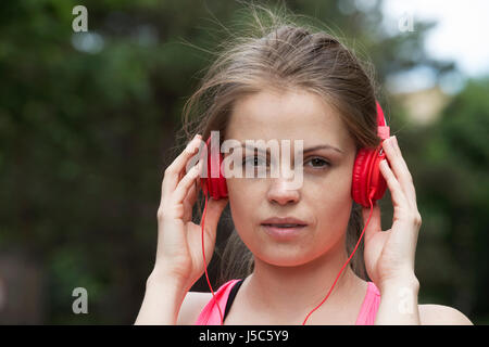 Aktive Frau Musik über Kopfhörer hören, wie sie außerhalb Übungen. Aktion und gesunden Lifestyle-Konzept. Stockfoto