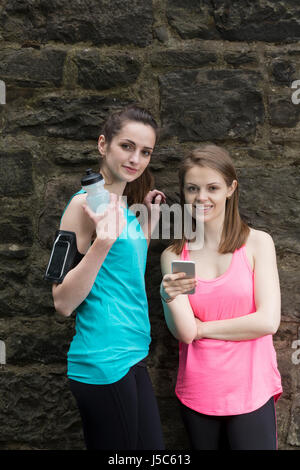 Zwei Läuferinnen, Austausch von Informationen über dort Smartphone nach gehen für einen Lauf.  Aktion und gesunden Lifestyle-Konzept. Stockfoto