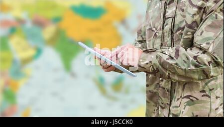 Digital Composite Soldaten Mittelteil mit Tablette gegen verschwommen Karte Stockfoto