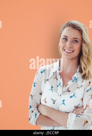 Digital Composite Porträt von lässig Geschäftsfrau stehend Arme gekreuzt vor orange Hintergrund Stockfoto