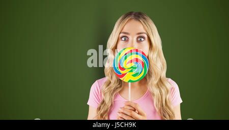 Digital Composite Porträt schockiert Frau den Mund mit Süßigkeiten vor grünem Hintergrund Stockfoto