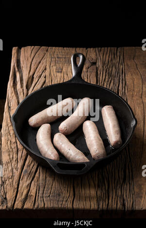 Rohe Gourmet Metzger Wurst in der Pfanne auf einem rustikalen hölzernen Hintergrund. Stockfoto