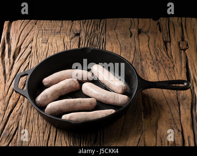 Rohe Gourmet Metzger Wurst in der Pfanne auf einem rustikalen hölzernen Hintergrund. Stockfoto