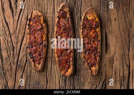 Türkische Pide-Pizza auf einem rustikalen Holztisch sitzend. Stockfoto