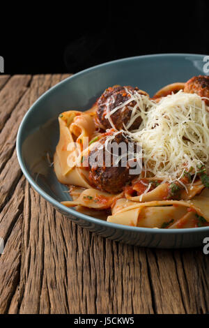 Italienische Fleischbällchen mit Nudeln, Tomatensauce und Parmesan. Auf einem rustikalen Holztisch sitzend. Stockfoto